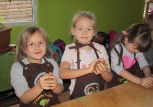 Dzieci ugniatają ciasto w rękach.