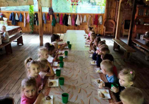 Dzieci jedzą pieczone ziemniaczki z sosem i surówką z kiszonej kapusty.