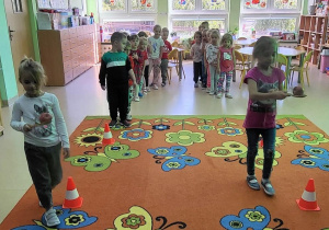Dzieci przenosza jabłka na łyżce.
