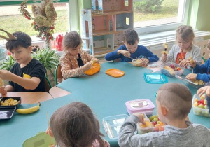 Dzieci wykonują owocowe szaszłyki.