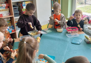 Dzieci wykonują owocowe szaszłyki.