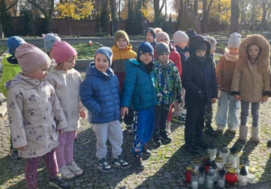 Żabki zapalają znicze przy grobach żołnierzy.