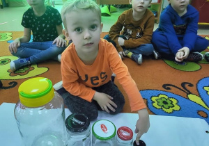 Chłopiec ustawia słoiki od największego do najmniejszego.