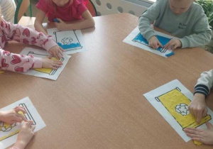 Dzieci wyklejają plasteliną kosze na śmieci.