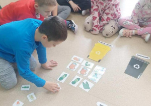 Chłopiec wkłada śmieci do odpowiedniego kosza.