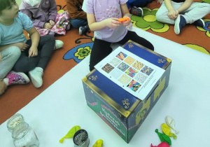 Dziewczynka za pomocą zmysłu dotyku określa co znajduje się w balonie.