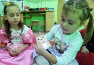 Dziewczynki z użyciem latarki zgadują, jaki bajkowy bohater ukrył się za drzwiami zamku.