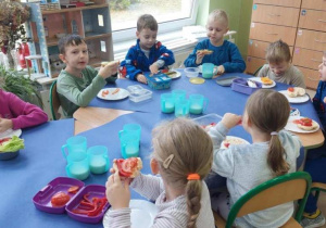 Dzieci jedzą zrobione kanapki.