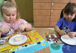 Dziewczynki wkładają wykałaczki–kolce jeża w masę solną.