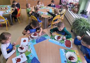 Dzieci malują jeże z masy solnej brązową farbą.