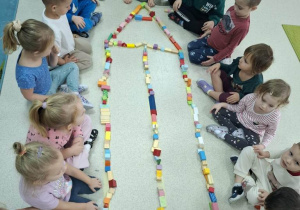 Dzieci układają kredkę z klocków.
