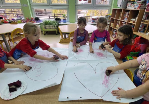 Przedszkolaki malują serca burakiem.
