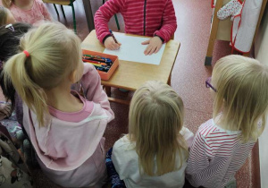 Dziewczynka z zakrytymi oczami rysuje misia.