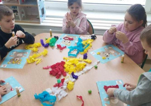 Żabki wylepiają misie kulkami z bibuły.