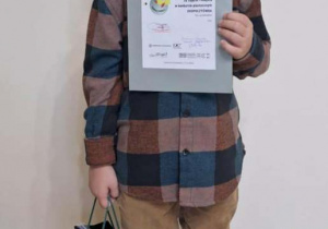 Chłopiec z dyplomem i nagrodą za zajęcie I miejsca w konkursie.