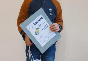Chłopiec z dyplomem i nagrodą za zdobycie wyróżnienia w konkursie.