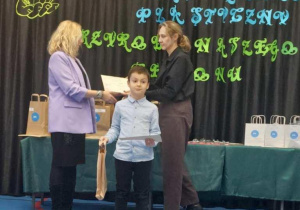 Chłopiec odbiera dyplom i nagrodę