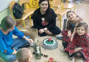 Rodzice wspólnie z dziećmi robią stroiki świąteczne.