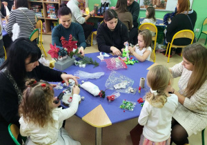 Rodzice wspólnie z dziećmi wykonują stroiki świąteczne.