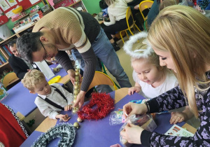 Rodzice wspólnie z dziećmi wykonują stroiki świąteczne.