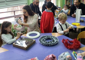 Rodzice wspólnie z dziećmi wykonują stroiki świąteczne.