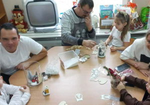 Dzieci wspólnie z rodzicami przygotowują świąteczne lampiony.