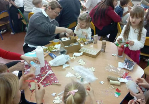 Dzieci wspólnie z rodzicami przygotowują świąteczne lampiony.