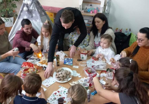 Dzieci wspólnie z rodzicami przygotowują świąteczne lampiony.