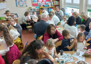 Dzieci wspólnie z rodzicami przygotowują świąteczne lampiony.