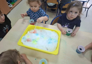Dzieci malują na śniegu przy pomocy pipet i zabarwionej wody