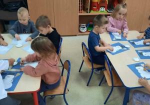 Dzieci malują farbami sylwety bałwanków