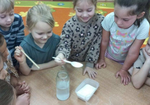 Dziewczynki rozpuszczają sól w wodzie do eksperymentu lodowe kryształy