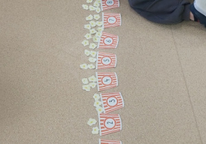 Żabki wkładają do pudełek odpowiednią ilość popcornu