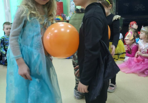 Dziewczynka z chłopcem tańczą z balonem