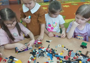 Dziewczynki konstruują budowlę z klocków.