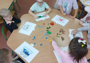 Dzieci układają klocki w wagonikach.