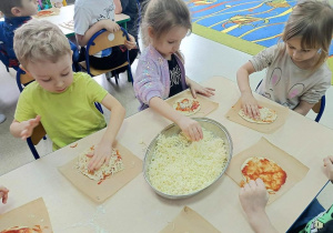 Dzieci nakładają na placek swoje ulubione składniki.