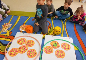 Chłopiec układa pizze do ilości kropek na kostce.