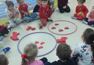 Przedszkolaki wkładają do kół odpowiednią ilość serduszek