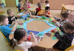 Dzieci przelewają wodę z kubeczka do kubeczka z użyciem pipet.