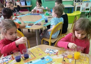 Dziewczynki przelewają wodę z kubeczka do kubeczka z użyciem pipet.