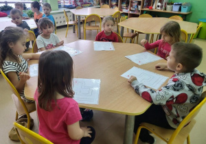 Przedszkolaki słuchają instrukcji do wykonania zadania.