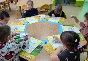 Dzieci malują obrazek przedstawiający czapkę farbami z użyciem patyczków higienicznych.