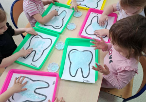 Dzieci wykonują pracę plastyczną z wykorzystaniem pasty do zębów.