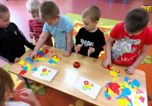 Chłopcy układają obrazek z figur geometrycznych