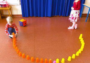 Chłopiec zbiera kubeczki według wyrzuconej liczby