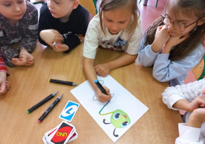 Dziewczynka rysuje kropki na gąsiennicy