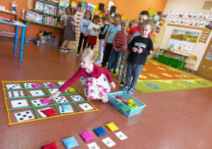 Dziewczynka układa woreczki według kodu