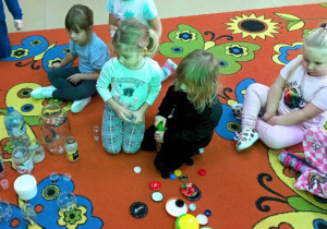 Dziewczynki dopasowują nakrętki do pojemników