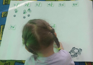 Dziewczynka dopasowuje ilość pand i ich tropów do cyfry